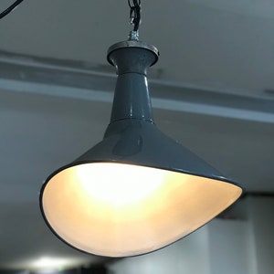 May include: A gray metal pendant light with a wide, curved shade. The light is on and illuminating the room.
