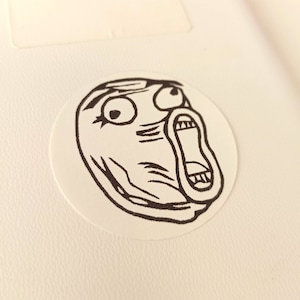 May include: A black and white illustration of a surprised face with a wide open mouth and large eyes. The face is drawn in a simple, cartoon style.
