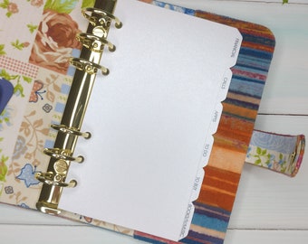 May include: A fabric-covered personal planner with a gold-toned six-ring metal binder mechanism. The interior features floral and striped patterns. A white tabbed divider is visible with text labels: FINANCIAL, CALLS, APPTS, TO DO, TO BUY, BOOKS/TV/MUSIC.