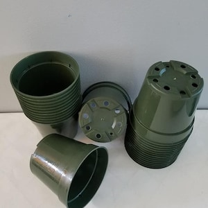 May include: A stack of dark green plastic plant pots. The pots are stacked in a pile and are ready to be used for planting.