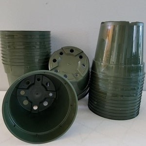 May include: A collection of dark green plastic plant pots. Some pots are stacked, while others are overturned, revealing drainage holes. The pots are cylindrical with a slightly flared rim, suitable for various plants.