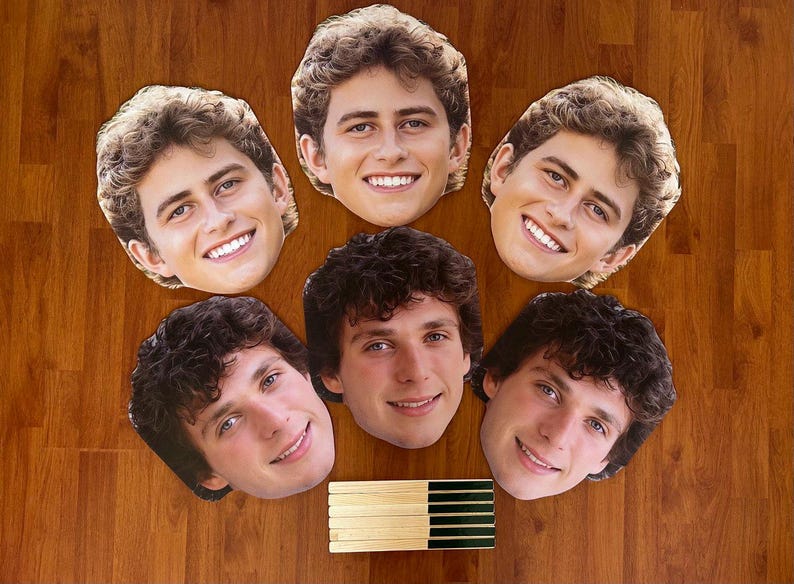 May include: Six paper face masks of young men with brown hair. The masks are printed with realistic images of the men's faces.