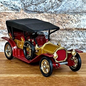 May include: A red and gold vintage toy car with a black fabric top. The car has a detailed design and is a classic model.