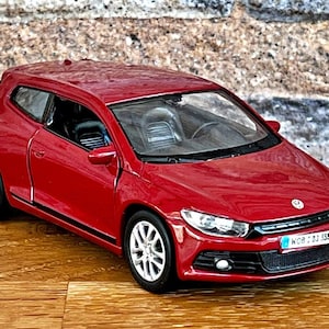 May include: A red Volkswagen Scirocco model car with black trim and a license plate that reads "WOB 2 DJ 338".