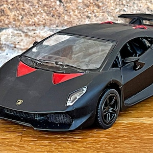 May include: Black toy car model of a Lamborghini with red accents and a rear spoiler.