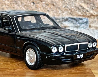 以下が含まれることがあります： 白い「XJ6」ナンバープレートが付いた黒いジャガーXJ6のモデルカー。この車は、黒い内装とクロムのアクセントが施された詳細なレプリカです。