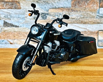 May include: A black motorcycle with a round headlight, curved handlebars, and side storage compartments. The motorcycle has a black seat, tires, and fenders. The bike is on a wooden surface.