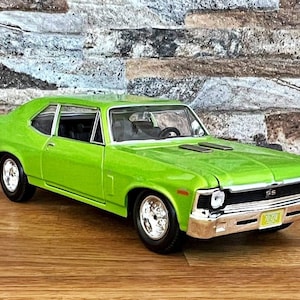 May include: A lime green 1970 Chevrolet Nova SS muscle car model with black accents and a chrome bumper. The car is sitting on a wooden surface.