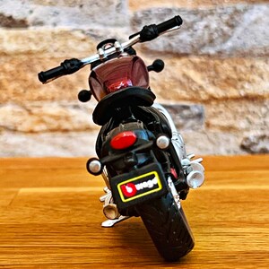 May include: A red and black toy motorcycle with a black license plate that says "b.toys".