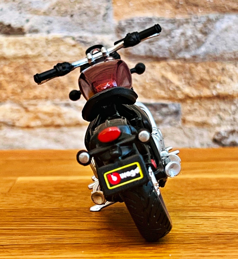 May include: A red and black toy motorcycle with a black license plate that says "b.toys".