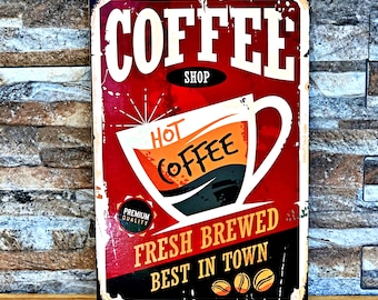May include: Red and white vintage style sign with the text "Coffee Shop" and a large illustration of a coffee cup with the text "Hot Coffee" inside. The sign also has the text "Fresh Brewed Best in Town" and a small circle with the text "Premium Quality".