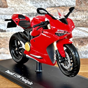 May include: A red Ducati 1199 Panigale motorcycle model on a black display stand. The motorcycle has a black windshield and black wheels.