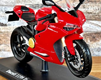 May include: A red Ducati 1199 Panigale motorcycle model on a black display stand. The motorcycle has a black windshield and black wheels.