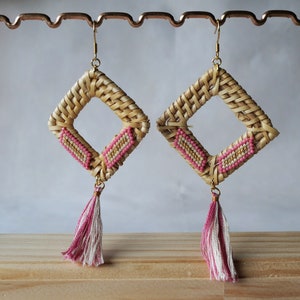 May include: A pair of woven rattan earrings with pink and white beaded accents and tassel drops.