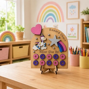 May include: Wooden reward chart featuring a unicorn, star, and rainbow design. The chart has the words "Reward Chart" and "Never Give Up!" The chart has pink, purple, and silver accents. The chart is on a wooden stand.