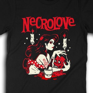 Puede incluir: Camiseta negra con un gr&aacute;fico rojo de una mujer con cabello negro largo sosteniendo una calavera. El gr&aacute;fico tambi&eacute;n incluye velas y corazones. El texto "NECROLOVE" est&aacute; impreso en rojo sobre el gr&aacute;fico.