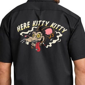 May include: Black short-sleeved work shirt with a cartoon rat graphic on the back. The graphic says "Here Kitty Kitty" and features a rat with a cigarette in its mouth.