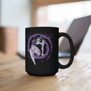 K&ouml;nnte beinhalten: Schwarze Keramiktasse mit einer lila und wei&szlig;en Illustration einer t&auml;towierten Frau, die in einer Wolke aus Flederm&auml;usen sitzt.