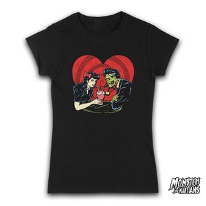 May include: Black t-shirt with a graphic of a zombie couple sharing a milkshake. The couple is surrounded by a red heart with a swirl pattern. The text "Monsters and Martians" is in the bottom right corner.