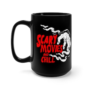 Peut inclure: Une tasse en c&eacute;ramique noire avec un graphique blanc d'une main sortant de la fum&eacute;e avec le texte "Scary Movies and Chill" en rouge.