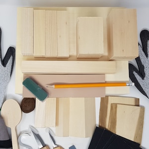 May include: A wood carving kit containing various sized wooden blocks, a pencil, a sanding block, a spoon, a carving knife, and two pairs of grey work gloves with green trim. The gloves have the text "Supreme" printed on them.