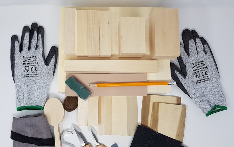 May include: A wood carving kit containing various sized wooden blocks, a pencil, a sanding block, a spoon, a carving knife, and two pairs of grey work gloves with green trim. The gloves have the text "Supreme" printed on them.
