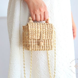 Girl in the white summer dress with small crossbody bag with gold chains strap