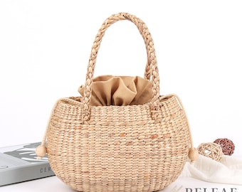 May include: A woven straw tote bag with a brown fabric lining and wooden handles. The bag has a rounded shape and is ideal for carrying everyday essentials.