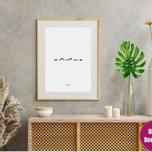 Puede incluir: Una impresión enmarcada con un marco dorado muestra un diseño minimalista en negro sobre un fondo blanco. El diseño presenta código Morse y la palabra "TRUST" debajo. La impresión se exhibe en un mueble de madera con objetos decorativos.