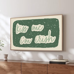 May include: A wooden media console with four doors and black legs. Above it hangs a framed art print with the text "Kiss me I'm Irish" in a green rectangle.