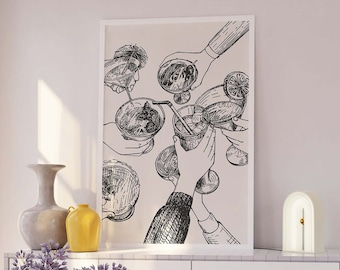 Op de afbeelding: Een zwart-witte lijntekening van mensen die glazen met cocktails omhoog houden. De tekening is ingelijst en hangt aan een witte muur boven een witte commode met gouden beslag.