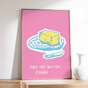 May include: A pink poster with a cartoon drawing of a stick of butter on a blue and white patterned plate with a blue knife. The text on the poster says "Pass the butter please."