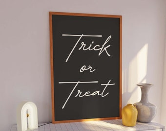 Może przedstawiać: Czarny, oprawiony napis z tekstem "trick or treat" napisanym białym, ozdobnym pismem. Napis stoi na białej komodzie z białą lampą i dwoma wazami.
