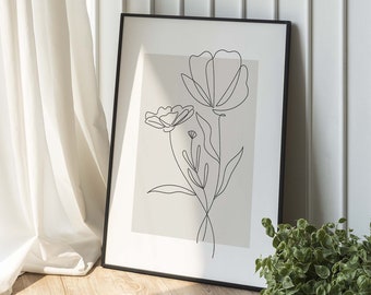 Könnte beinhalten: Ein schwarzer gerahmter Druck mit einer Linienzeichnung von Blumen auf beigefarbenem Hintergrund. Der Druck lehnt an einer weißen Wand mit weißen Wandvertäfelungen.