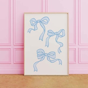 May include: A framed print with a white background and four blue bows drawn on it. The print is hanging on a pink wall.