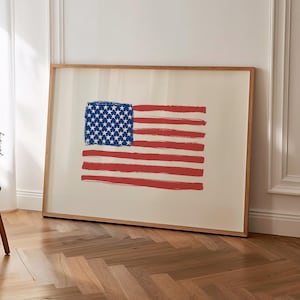 Puede incluir: Una impresión enmarcada de la bandera estadounidense. La bandera presenta un rectángulo azul con estrellas blancas en la esquina superior izquierda y rayas rojas y blancas. La obra de arte está en un marco de madera.