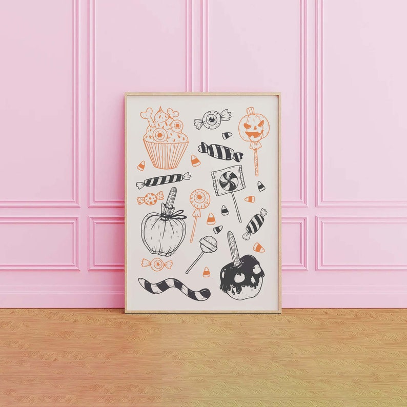 K&ouml;nnte beinhalten: Ein gerahmter Druck mit wei&szlig;em Hintergrund und schwarzen und orangefarbenen Illustrationen von Halloween-Leckereien, darunter ein Cupcake, Candy Corn, Lutscher, ein K&uuml;rbis und ein Karamellapfel.