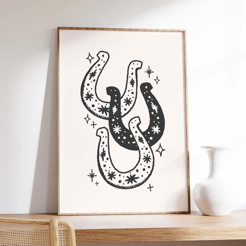 May include: Black and white illustration of three horseshoes with a star pattern. The horseshoes are overlapping and are surrounded by small stars.