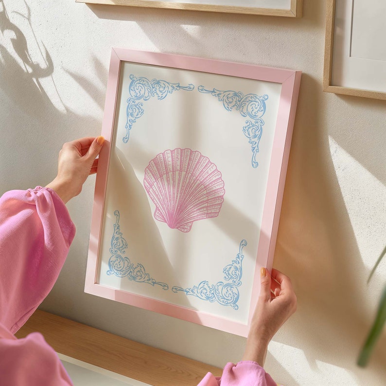 Puede incluir: Una impresi&oacute;n enmarcada en rosa con un dise&ntilde;o de concha marina azul claro y blanco. La concha marina est&aacute; en el centro de la impresi&oacute;n y est&aacute; rodeada por un borde decorativo.