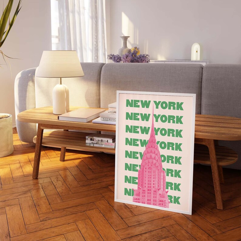 Pu&ograve; includere: Una stampa incorniciata con un'illustrazione rosa e verde di un grattacielo. Il testo "NEW YORK" &egrave; ripetuto in lettere verdi su uno sfondo rosa.
