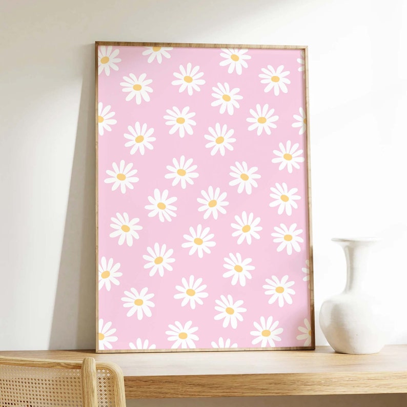 May include: A framed print with a pink background and a repeating pattern of white daisies with yellow centers.