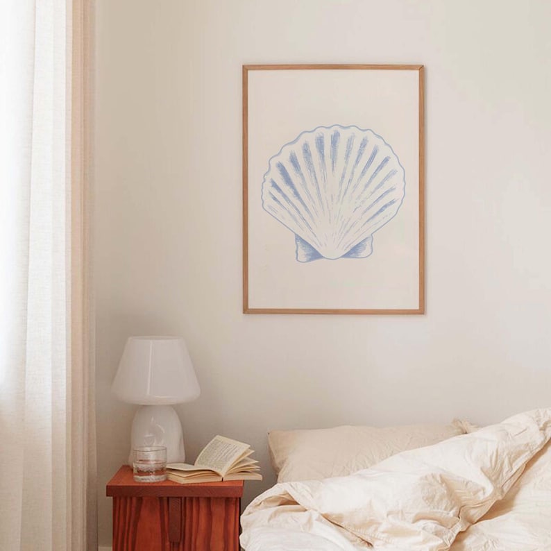 Pode incluir: Uma impress&atilde;o emoldurada de uma concha azul e branca sobre um fundo branco. A impress&atilde;o est&aacute; pendurada em uma parede branca em um quarto.