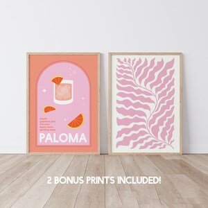 May include: Two framed prints, one with a pink background and a cocktail illustration with the text "PALOMA" and the ingredients listed, and the other with a pink and white abstract leaf design.