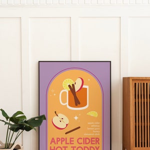 May include: A purple framed poster with a yellow background and a stylized illustration of a mug of apple cider hot toddy. The ingredients are listed below the mug: apple cider, whiskey, lemon juice, honey, and cinnamon stick. The text "APPLE CIDER HOT TODDY" is in bold, orange letters.