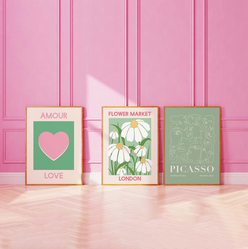 May include: Three framed art prints with a green background. The left print has a pink heart with the words "Amour" and "Love". The middle print has white daisies with the words "Flower Market" and "London". The right print has a line drawing of faces with the words "Picasso" and "The Modern French Painter".