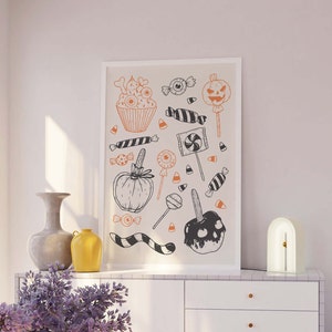 K&ouml;nnte beinhalten: Eine Schwarzwei&szlig;illustration von Halloween-Leckereien, darunter ein Cupcake, Candy Corn, ein Lollipop, ein Karamellapfel und ein K&uuml;rbis. Die Illustration ist auf wei&szlig;em Hintergrund.