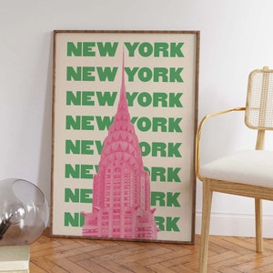 Pu&ograve; includere: Un poster con un'illustrazione rosa del Chrysler Building a New York City. Lo sfondo &egrave; beige con le parole "NEW YORK" ripetute in verde.