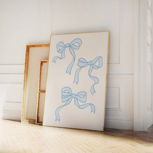 May include: A white canvas with a gold frame featuring four blue ribbon bows. The bows are drawn in a simple, elegant style.