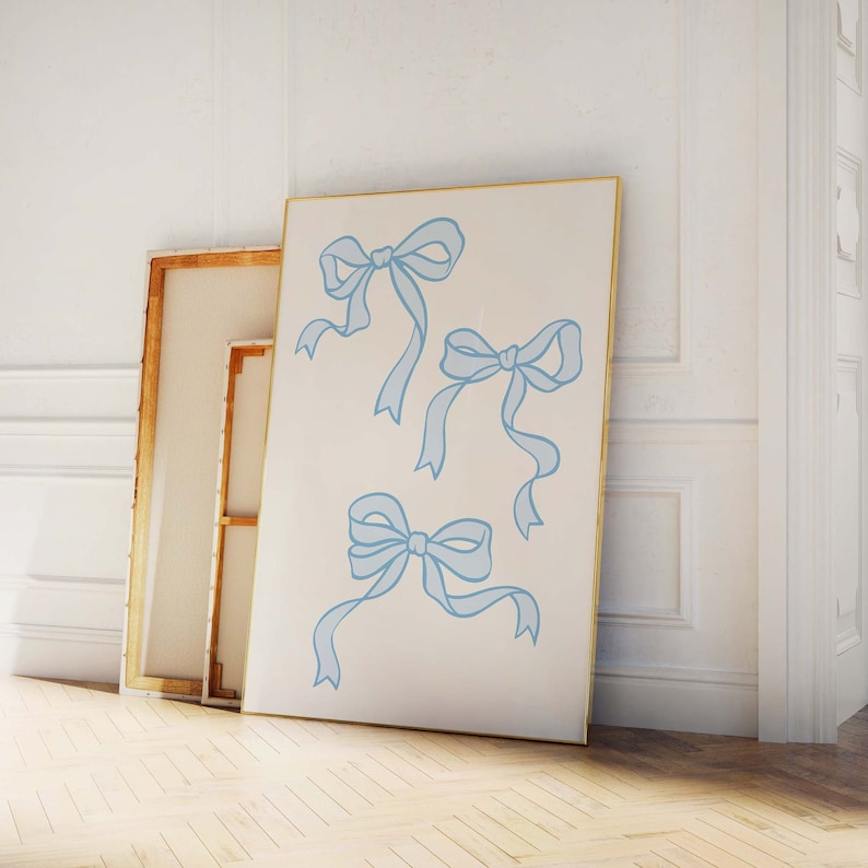May include: A white canvas with a gold frame featuring four blue ribbon bows. The bows are drawn in a simple, elegant style.