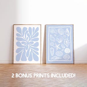 Pode incluir: Duas impress&otilde;es emolduradas com fundo azul claro e ilustra&ccedil;&otilde;es brancas. A impress&atilde;o &agrave; esquerda apresenta um design floral estilizado. A impress&atilde;o &agrave; direita apresenta uma cole&ccedil;&atilde;o de conchas.
